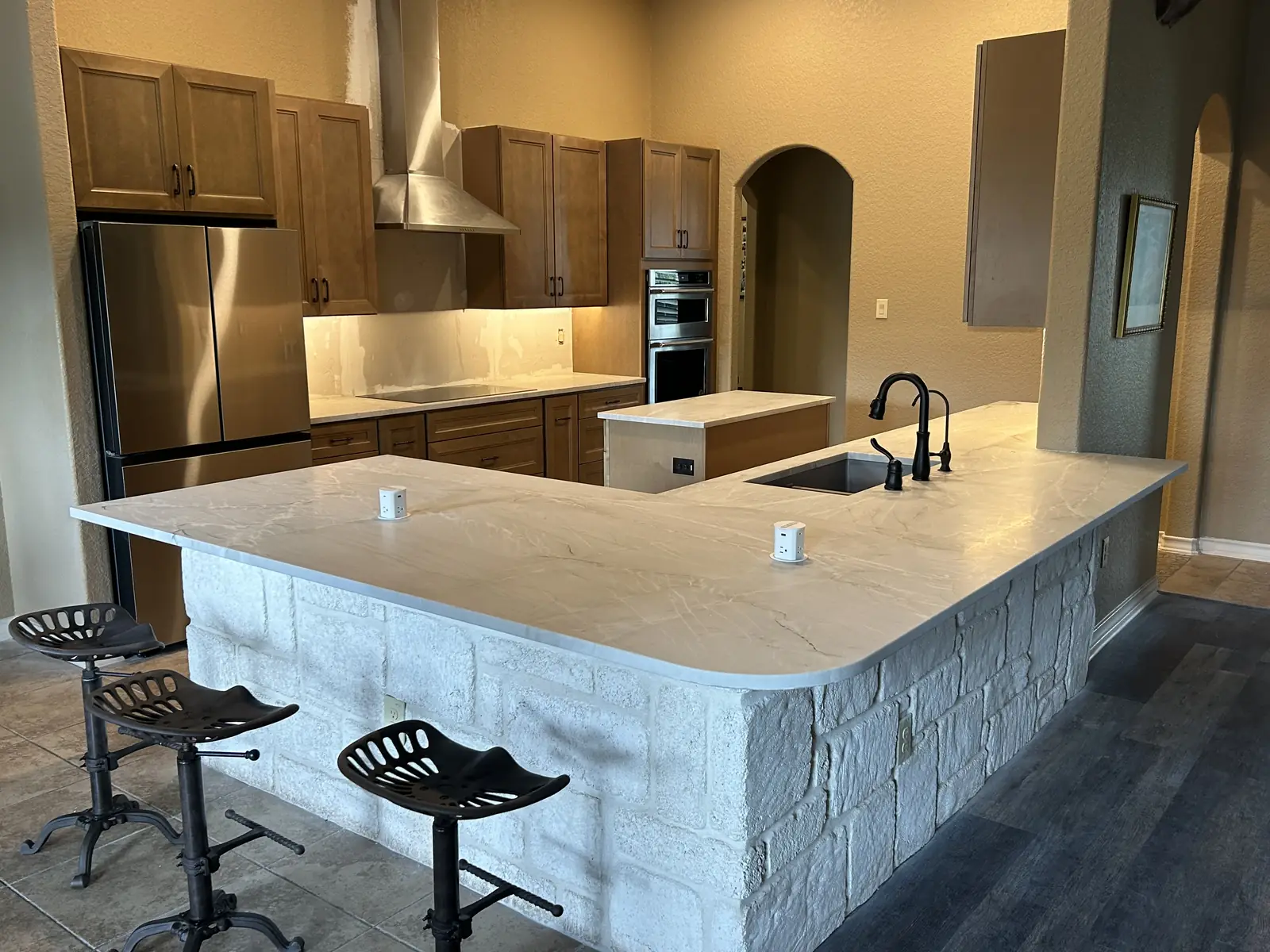 Finished Boerne kitchen island with stone facing and seating
