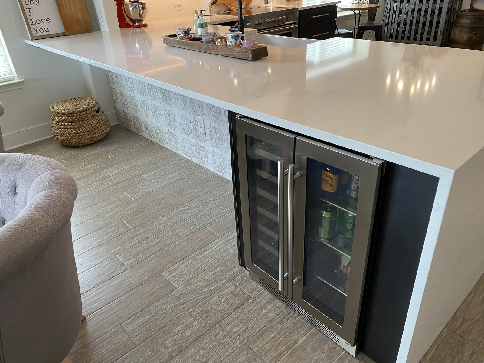 Kitchen island with a built in wine refrigerator and stone counter