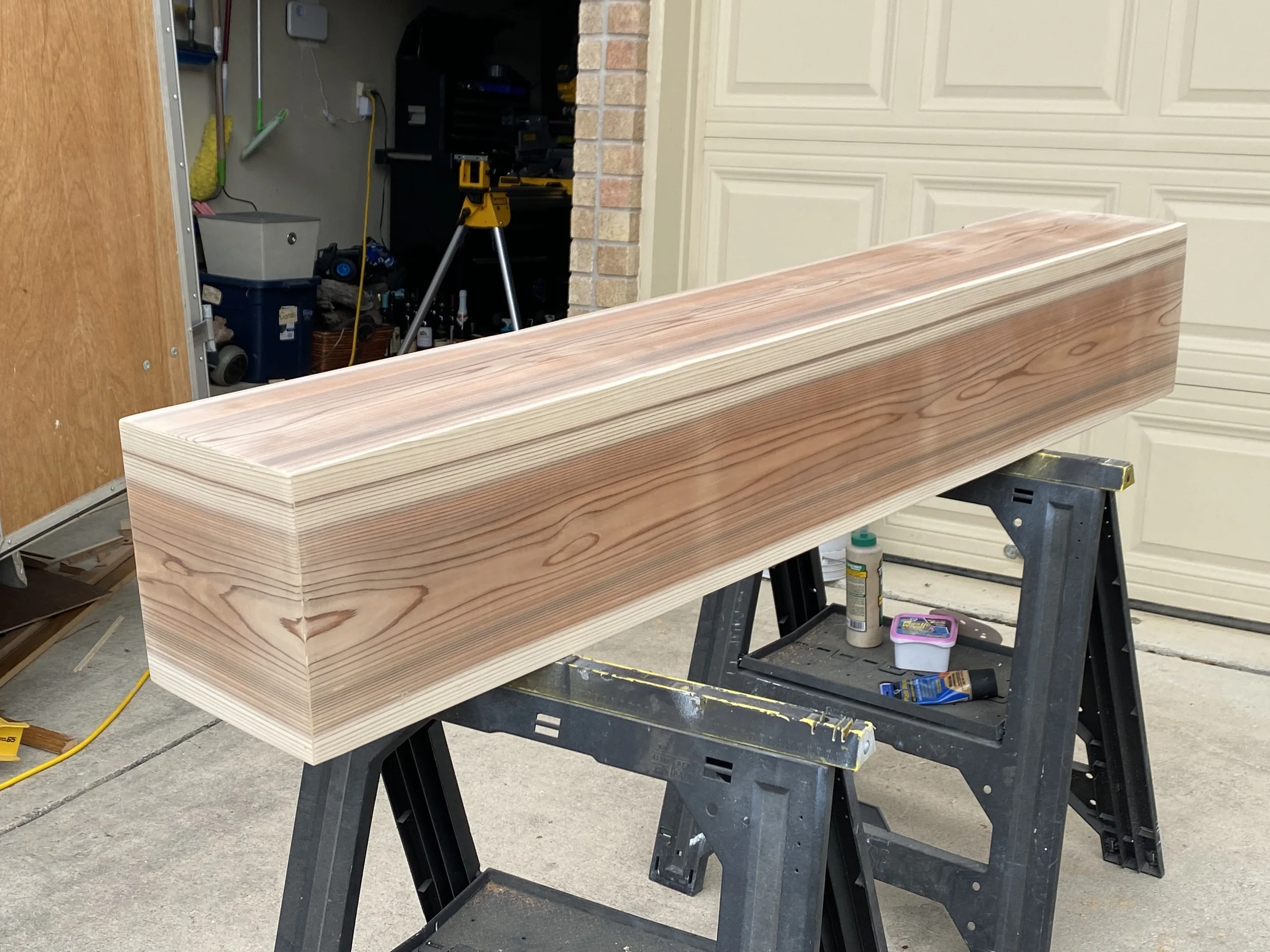 Cedar fireplace mantel on sawhorses in the shop before installation, mitred corners visible