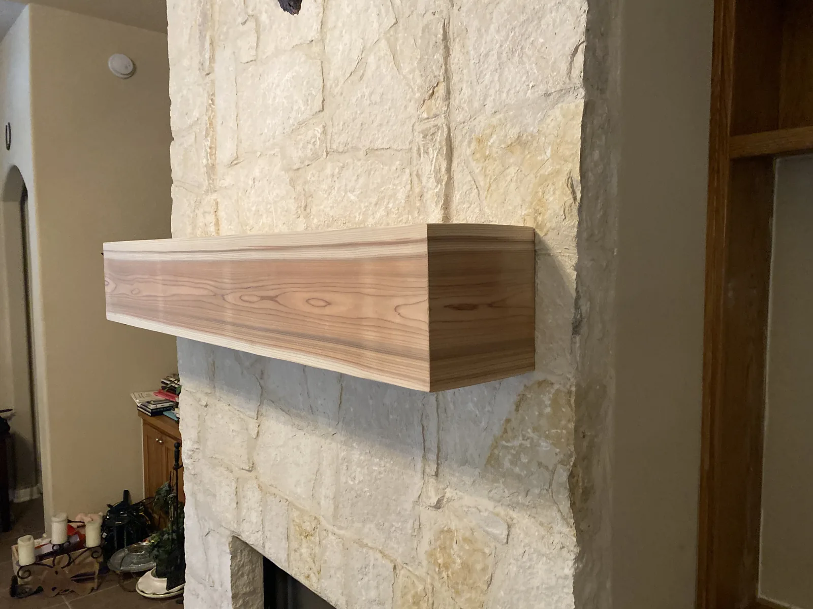 Cedar mantel installed on a limestone fireplace