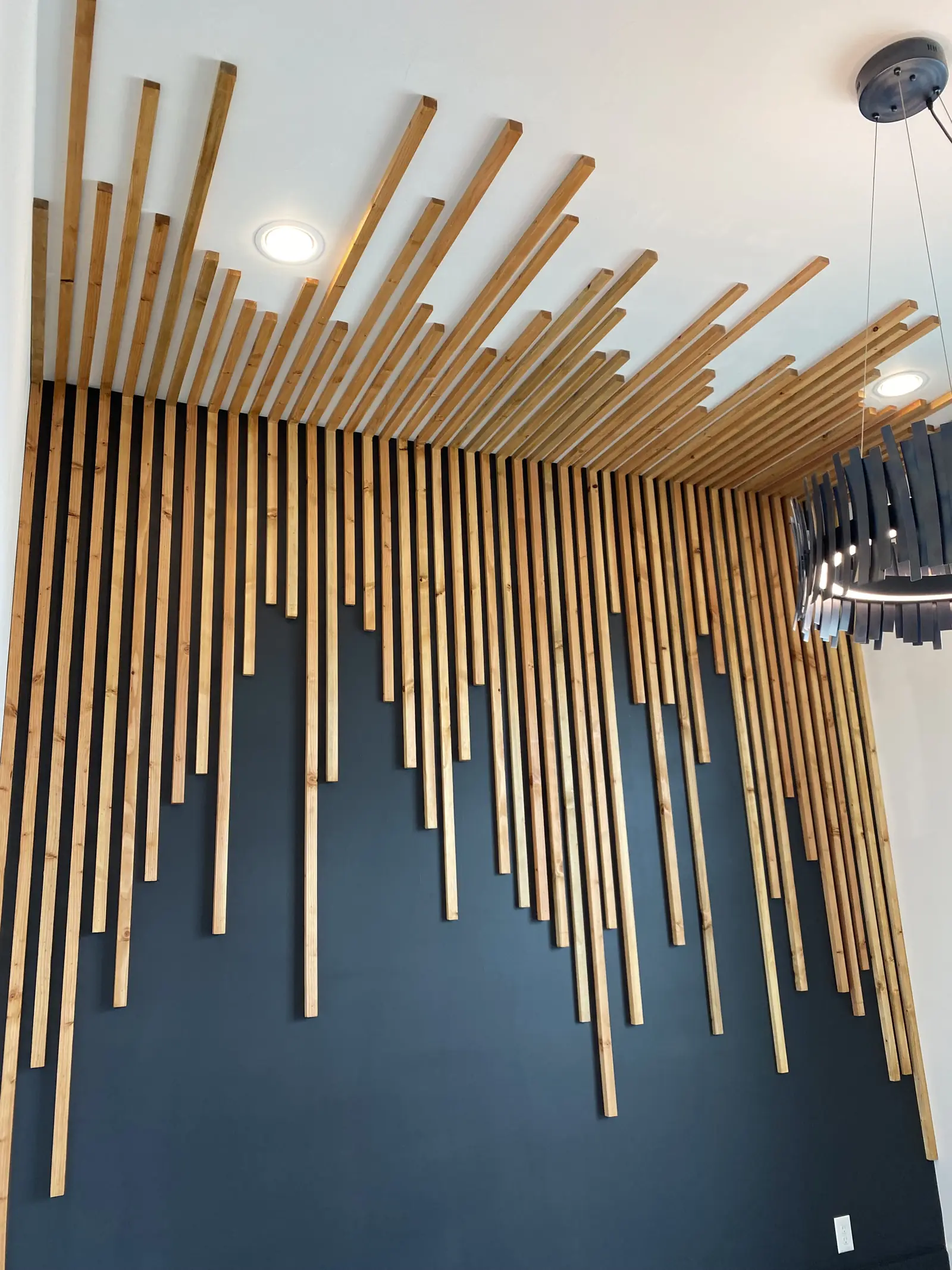 Geometric wood batten feature wall in gold against a deep navy painted wall