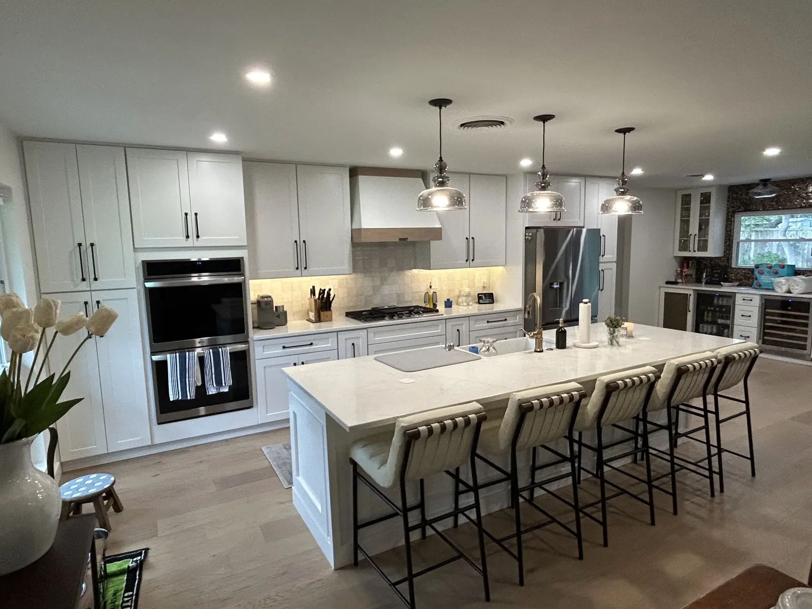 Kitchen with a wood wrapped range hood, quartz island and farmhouse sink