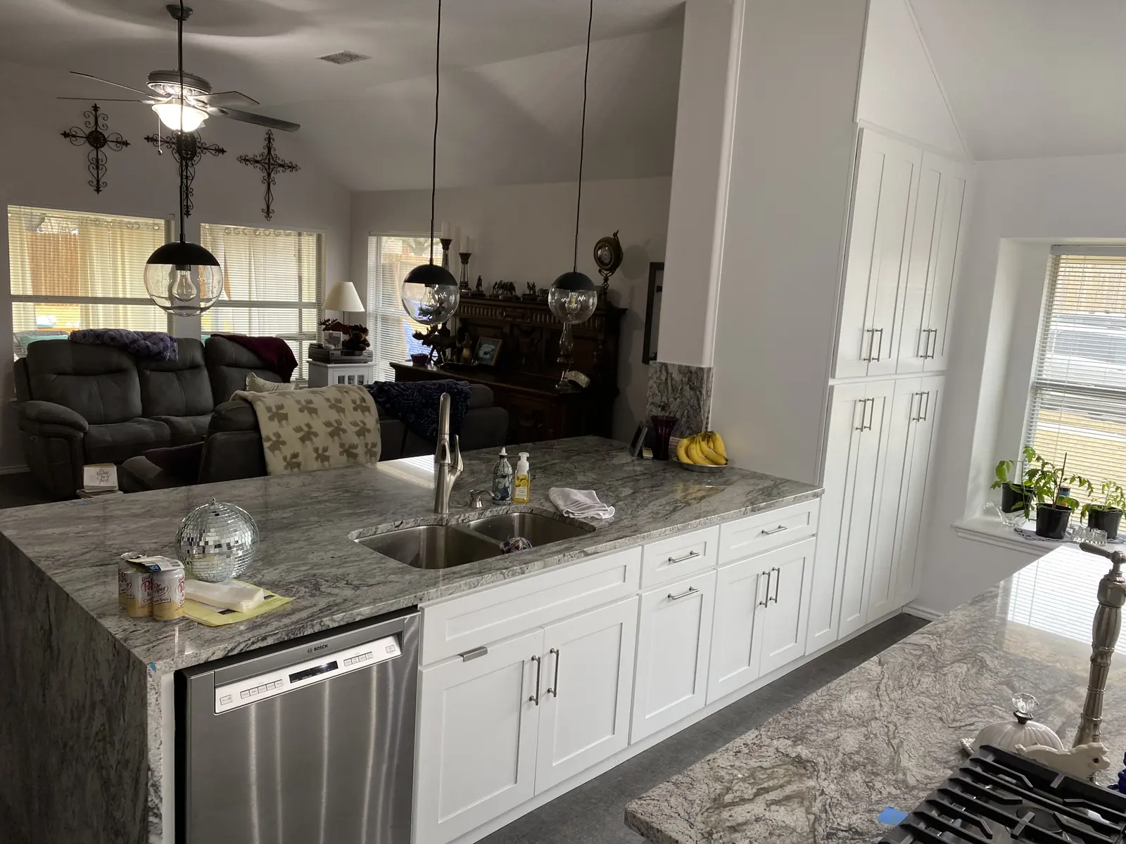 Kitchen run with heavy veined stone counters and white cabinetry