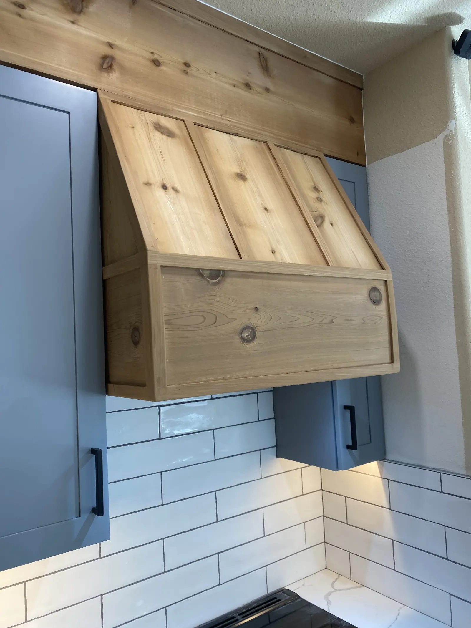 Hand built knotty cedar range hood above a cooktop