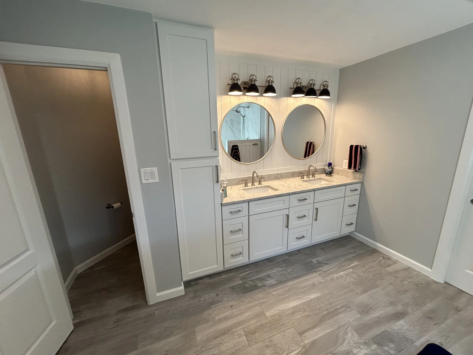 Remodeled bathroom with a white double vanity and round mirrors