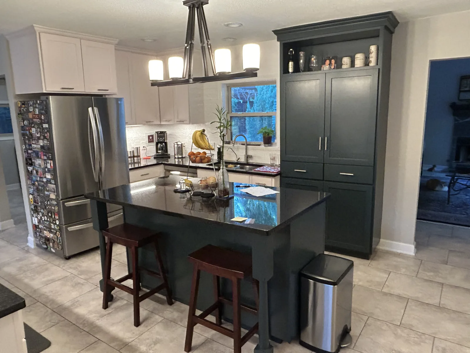 Terrell Hills kitchen with a dark island, pendant lighting and white cabinetry