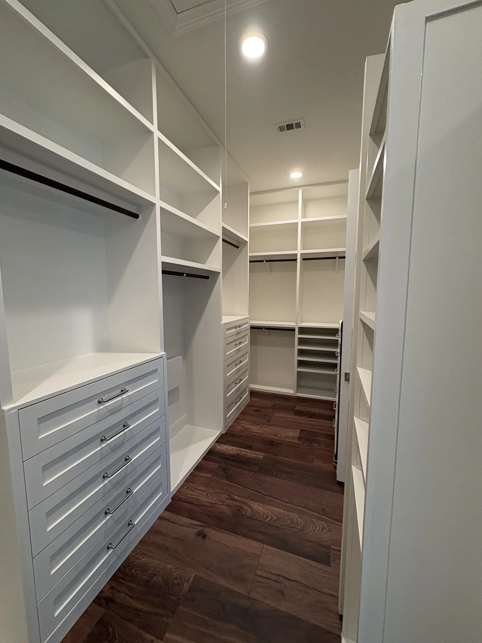 Walk in closet with a centre island of drawers and full height shelving