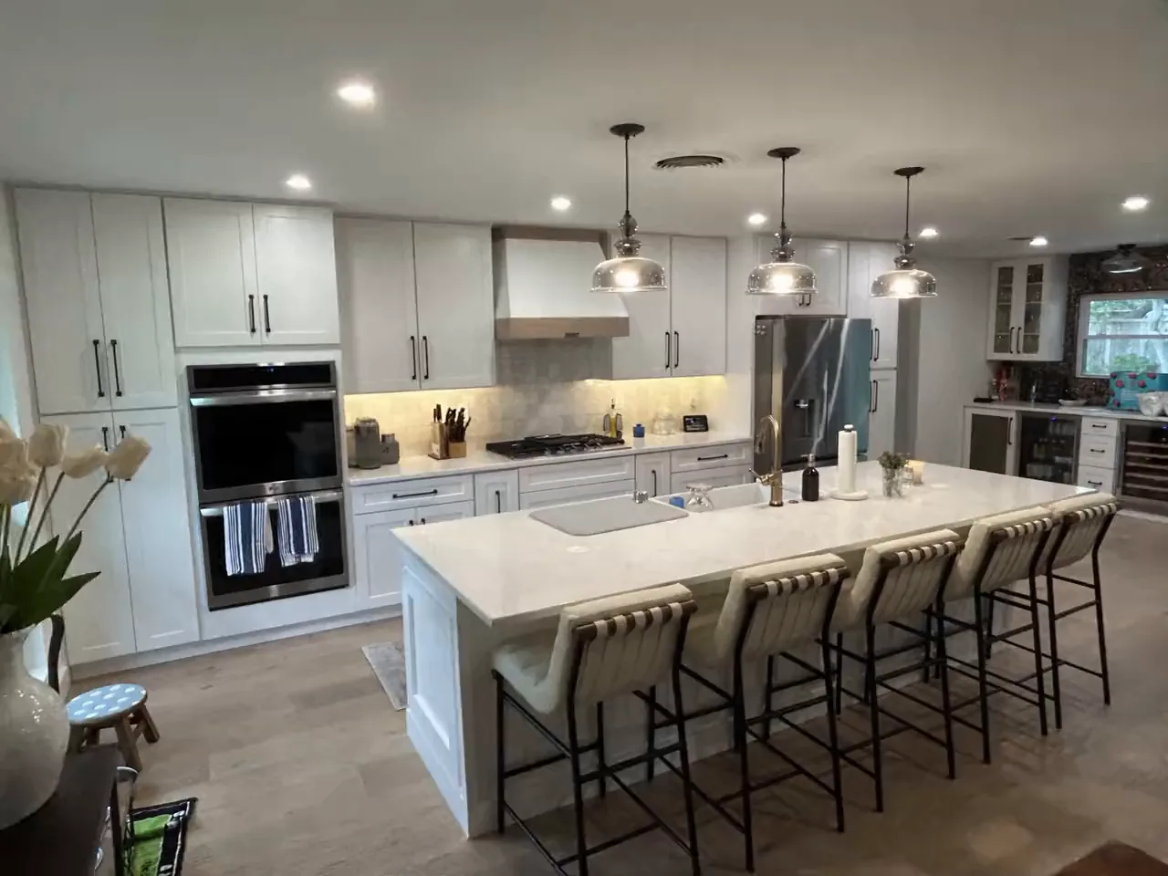 The same Hollywood Park kitchen after remodeling, with a quartz island, wood wrapped range hood and farmhouse sink
